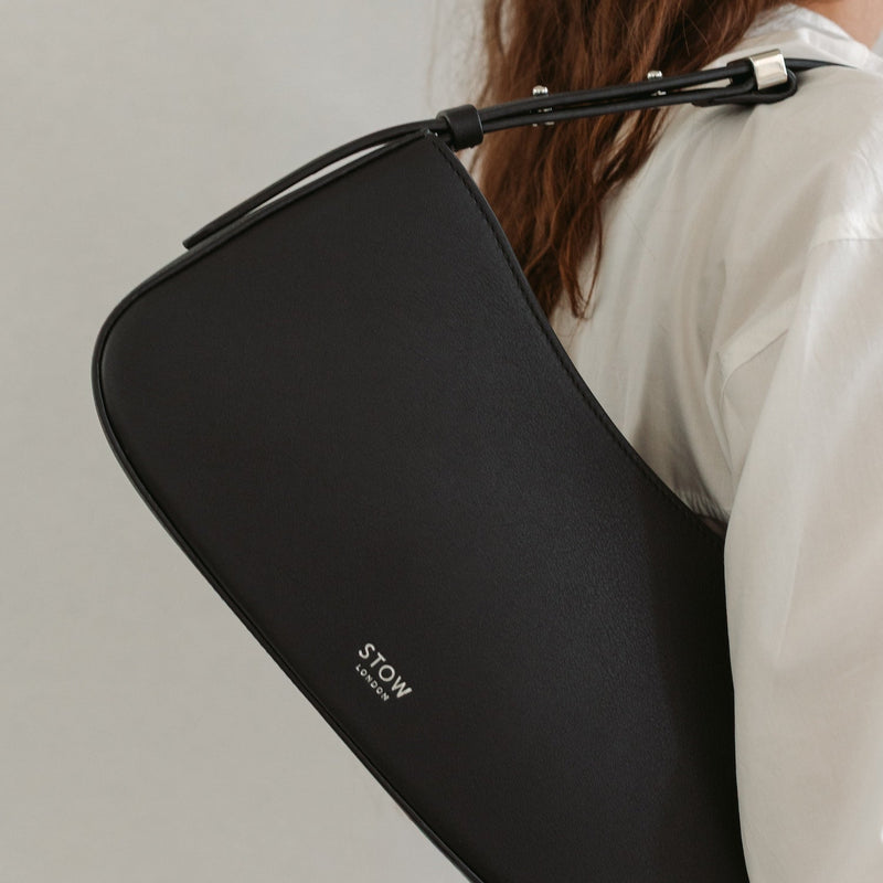 Close up of Model wearing STOW London's Post Shoulder bag in Black smooth leather featuring silver hardware and small embossed logo