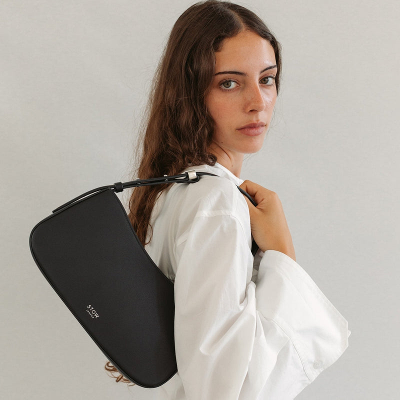 Model wearing STOW London's Post Shoulder bag in Black smooth leather on her shoulder featuring silver hardware