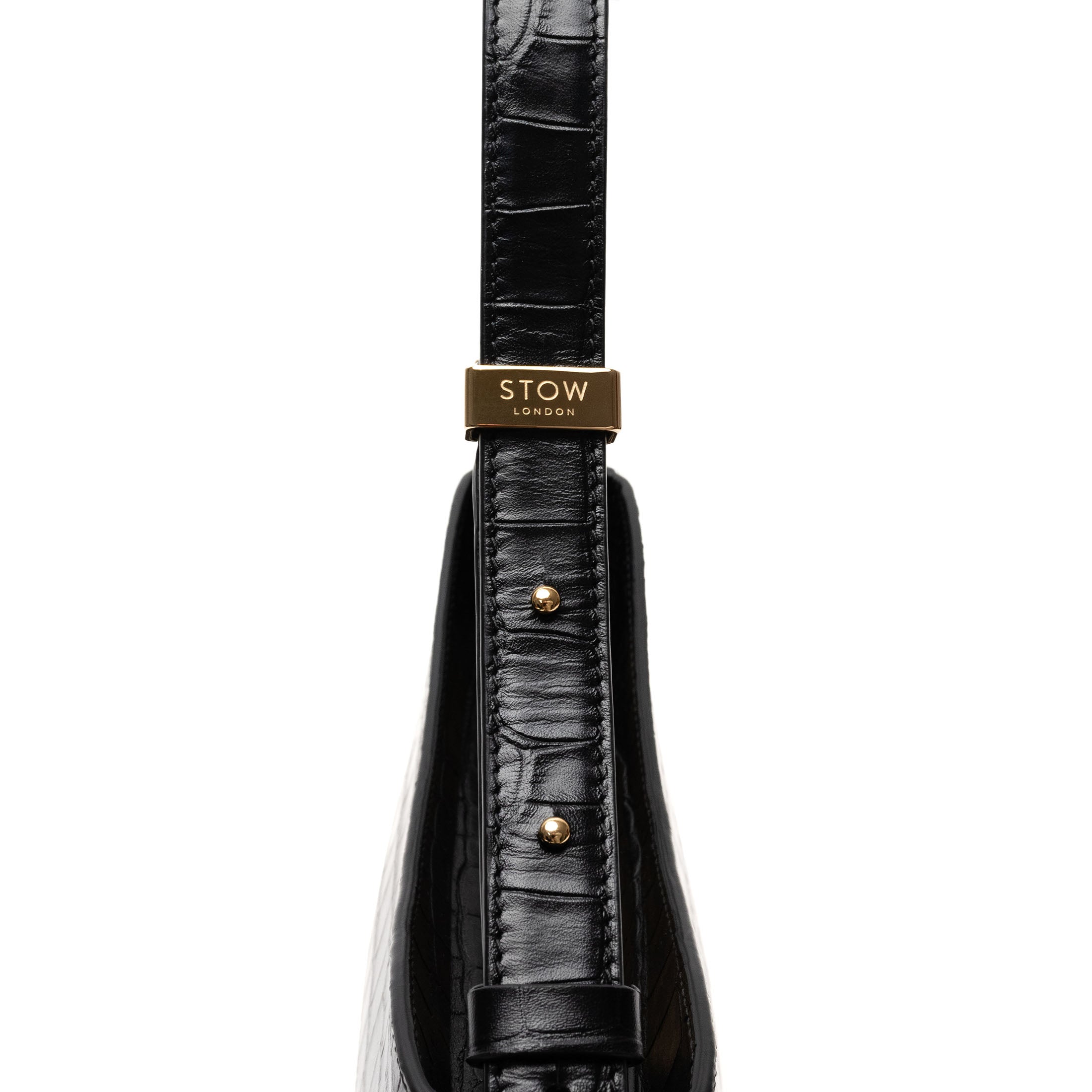 Close up of the strap, gold-coated stainless steel hardware and brand engraving on STOW London's Post Shoulder bag in Black Embossed Croc leather on a white background