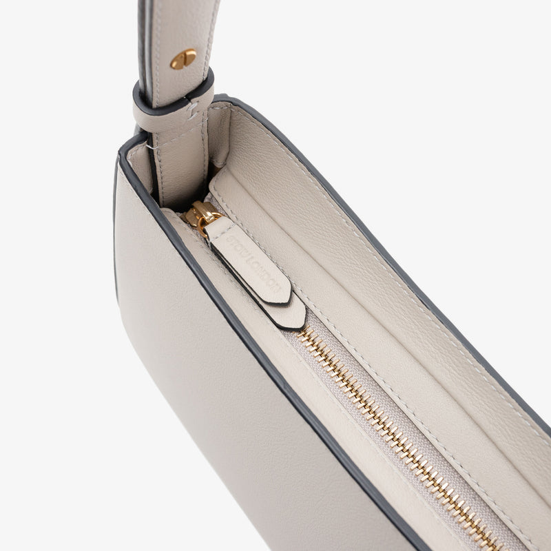Close up of the zip closure and STOW London embossed pull tabs on Stow London's Post Shoulder in Cloud Grey smooth leather on a light grey background featuring gold-coated stainless steel hardware