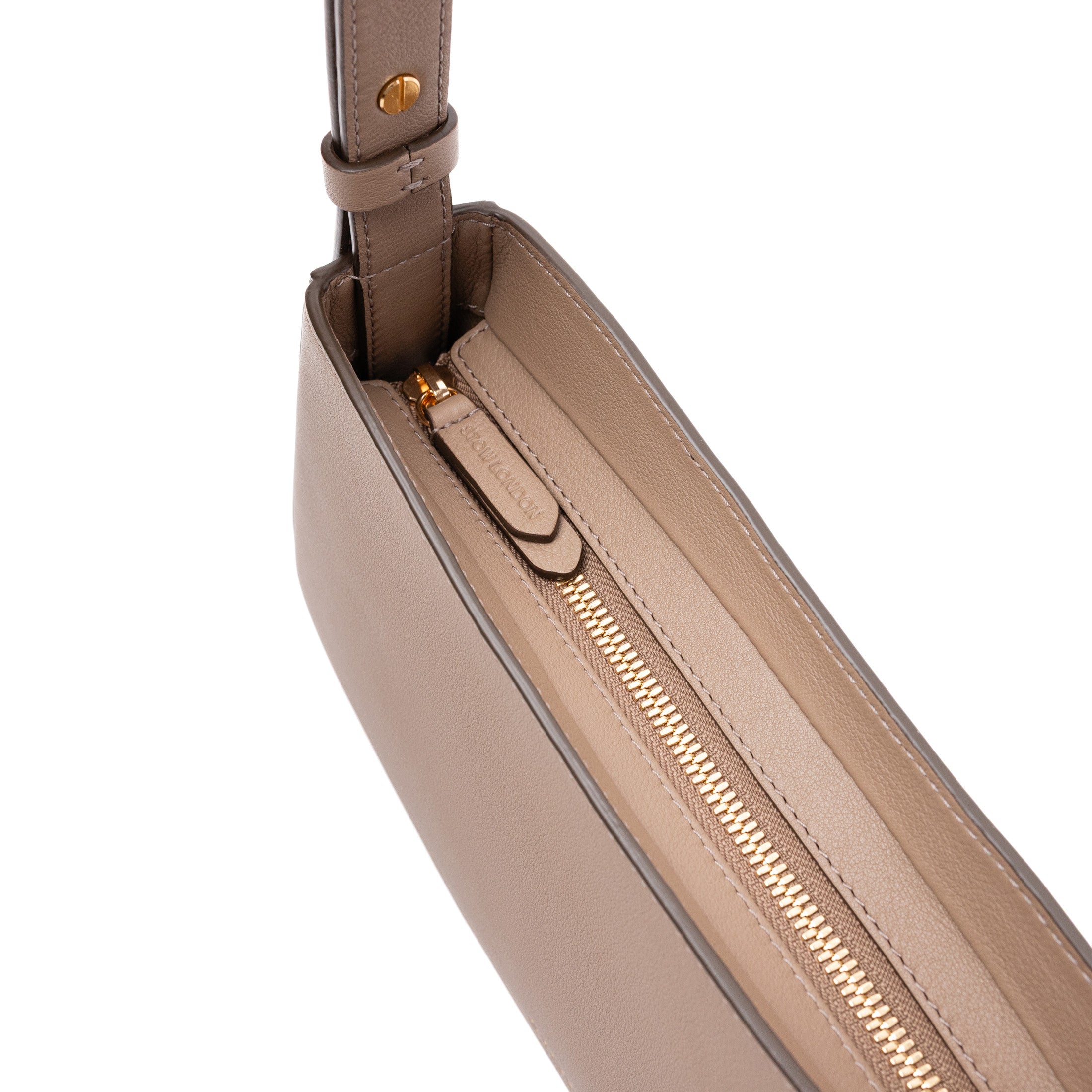 Close up of zip closure on STOW London's Post Shoulder bag in Warm Taupe smooth leather featuring gold-coated stainless steel hardware and brand engraving on pull tab on a white background