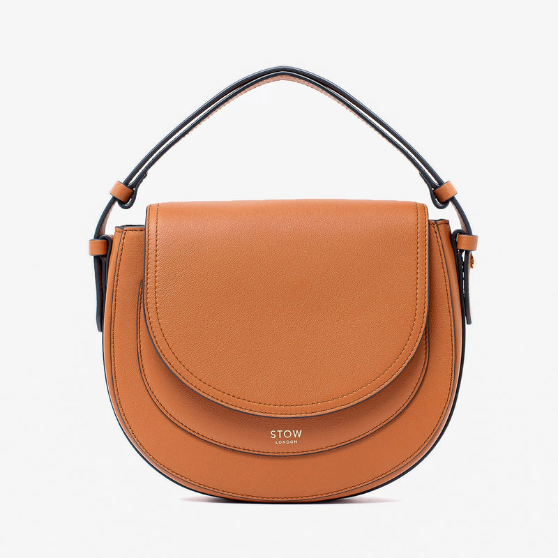 STOW London's Saddle bag in Earth Tan smooth leather with its short top handle on a light grey background