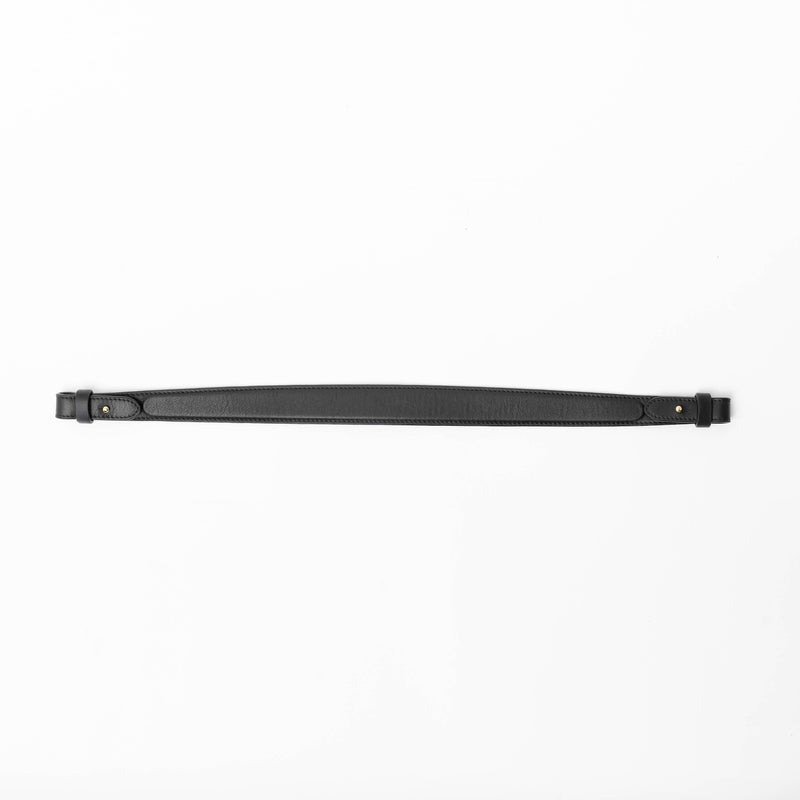 Detachable shoulder strap for STOW London's Curve, Midi Curve and East West in Black smooth leather on a light grey background featuring gold hardware 