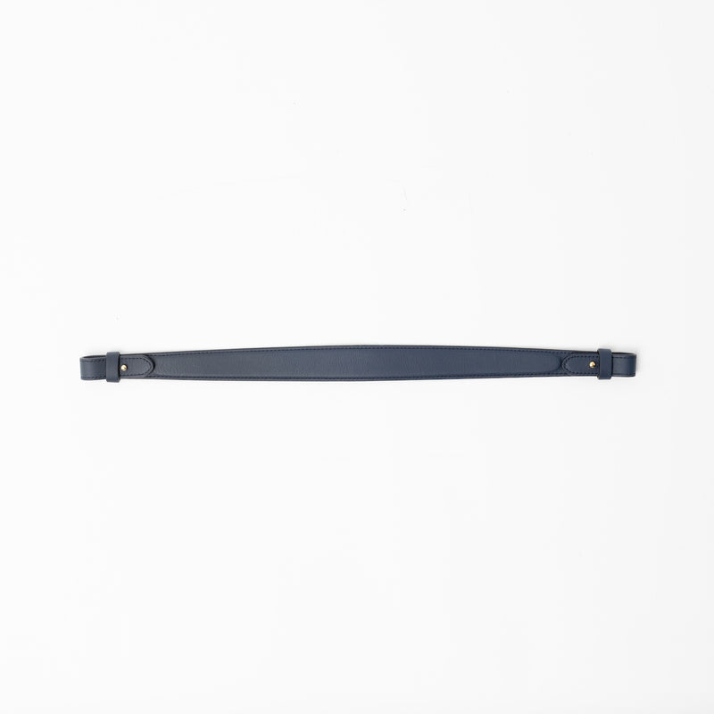 Detachable shoulder strap for STOW London's Curve, Midi Curve and East West in Navy smooth leather on a light grey background featuring gold hardware 
