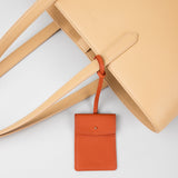 STOW Leather Multi Tag in Clay Orange pebbled leather shown hanging on Almond Leather Everyday Tote Bag by STOW.