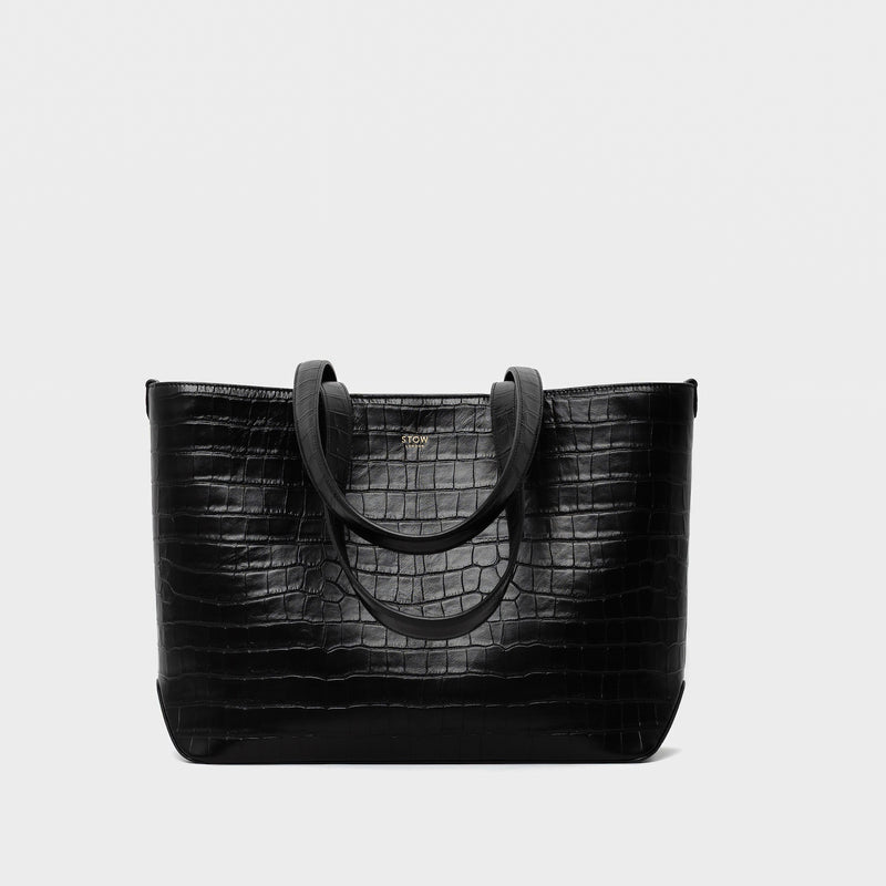 Stow London's Everyday Tote Bag in Black Embossed Croc leather on a light grey background featuring gold STOW logo