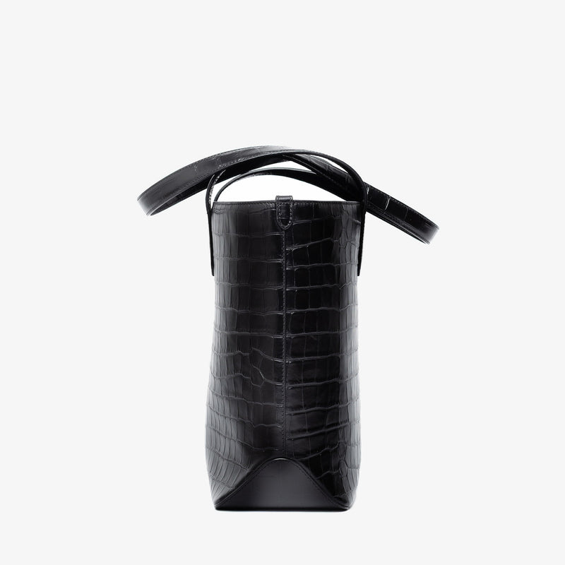 Side view of Stow London's Everyday Tote Bag in Black Embossed Croc leather on a light grey background