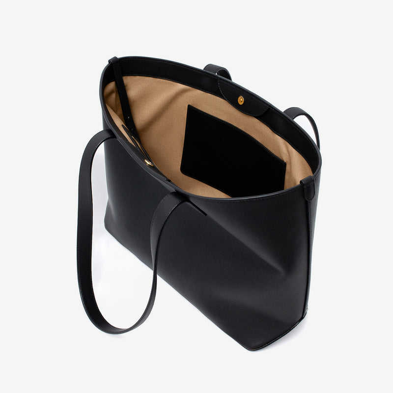 Stow London's Everyday Tote Bag in Black smooth leather with magnets open showing cotton interior and slip pocket on a light grey background