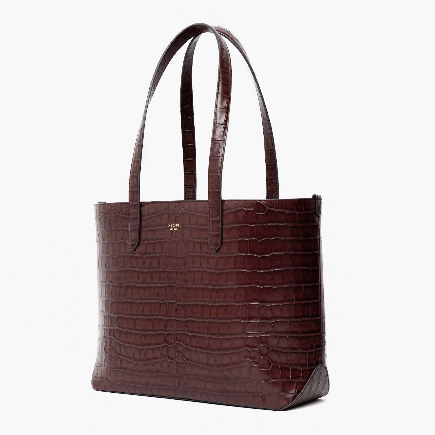 Off-axis view of Stow London's Everyday Tote Bag in Burgundy Embossed Croc leather on a light grey background featuring gold STOW logo
