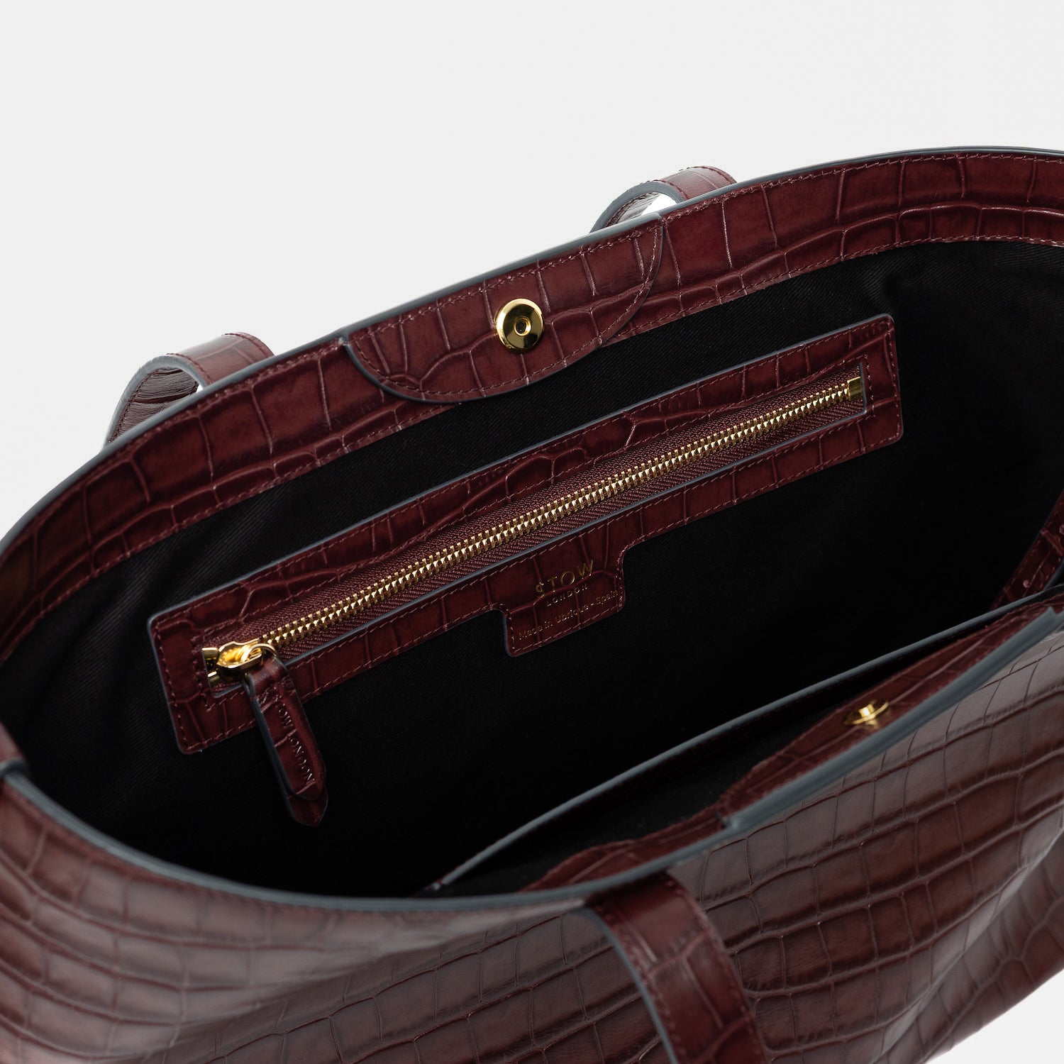 Close up of the interior of Stow London's Everyday Tote Bag in Burgundy Embossed Croc leather on a light grey background featuring the interior zip and slip pockets