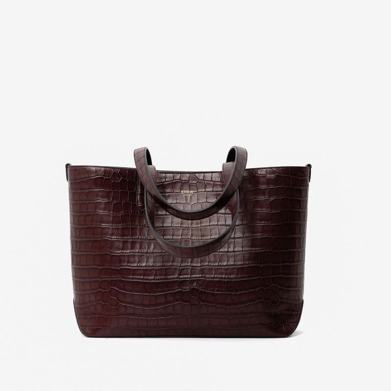 Stow London's Everyday Tote Bag in Burgundy Embossed Croc leather on a light grey background featuring gold STOW logo