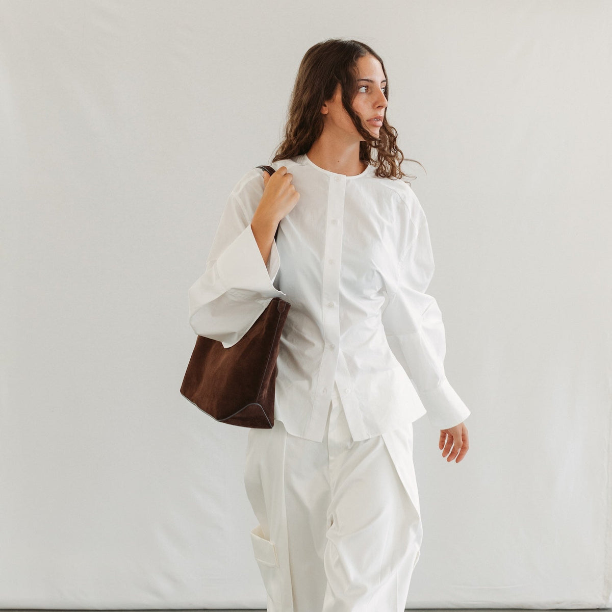 Model wearing STOW London's Everyday Tote bag in Chocolate suede featuring a small STOW London logo embossed on the front panel