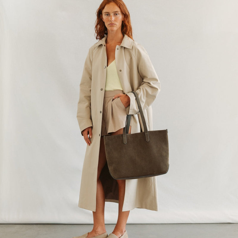 Model wearing STOW London's Everyday Tote bag in Dark Green suede featuring a small STOW London logo embossed on the front panel