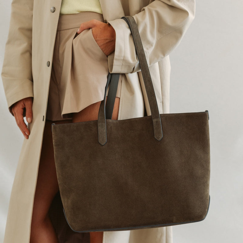 Model wearing STOW London's Everyday Tote bag in Dark Green suede featuring a small STOW London logo embossed on the front panel