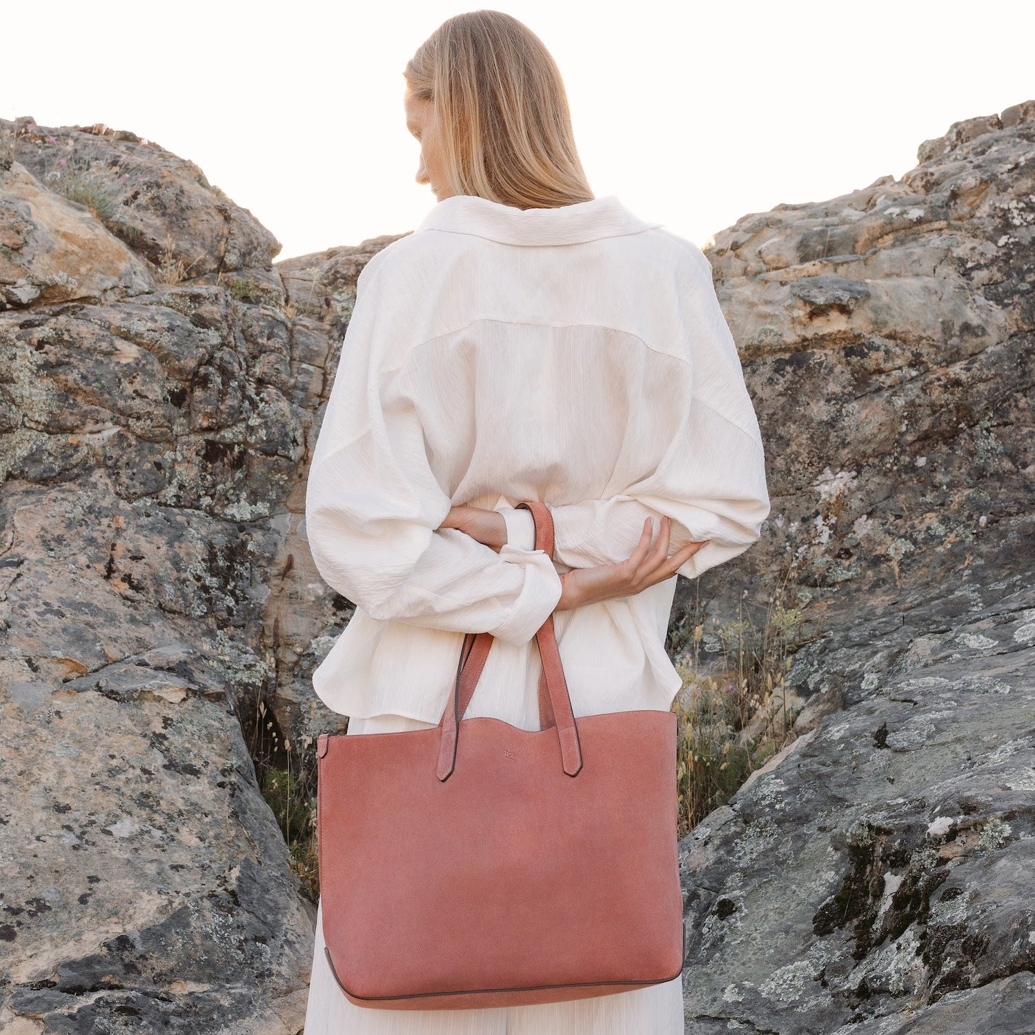 Model with STOW London's Everyday Tote bag in Hazy Blush suede featuring a small STOW London logo embossed on the front panel 