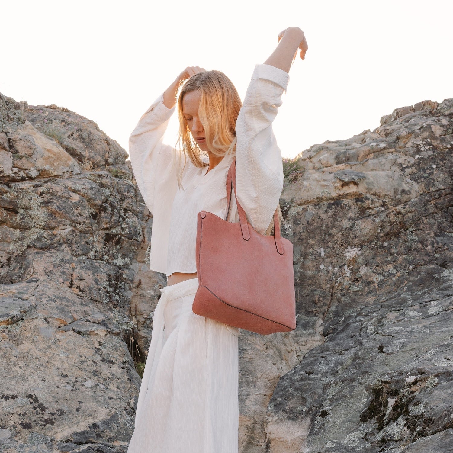 Model wearing STOW London's Everyday Tote bag in Hazy Blush suede on her shoulder featuring a small STOW London logo embossed on the front panel 