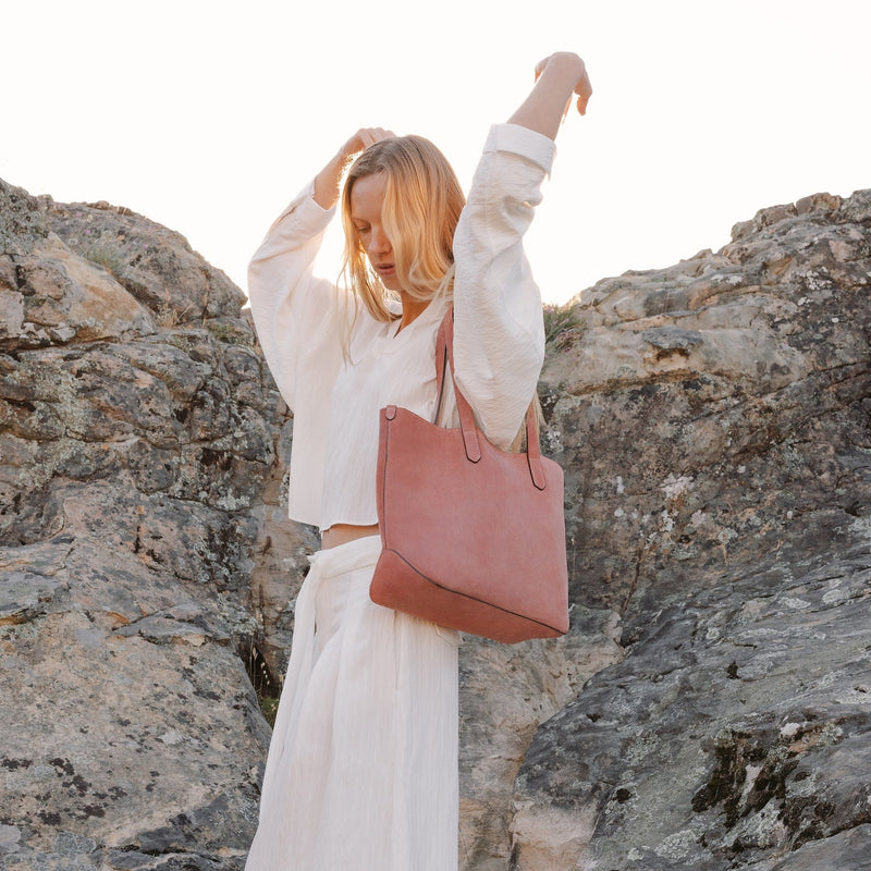 Model wearing STOW London's Everyday Tote bag in Hazy Blush suede on her shoulder featuring a small STOW London logo embossed on the front panel 