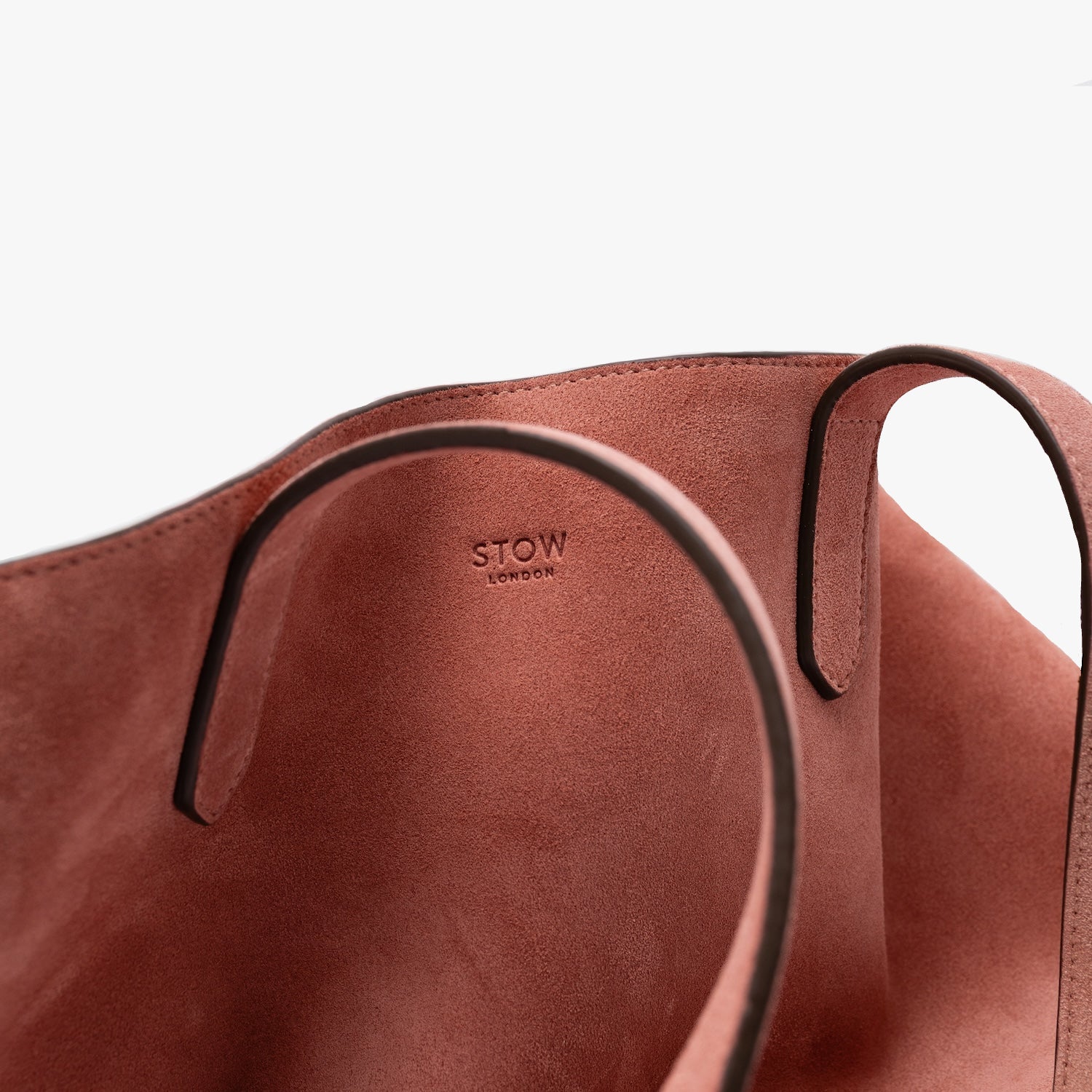 Close up of the small STOW London logo on the Everyday Tote bag in Hazy Blush suede on a light grey background 