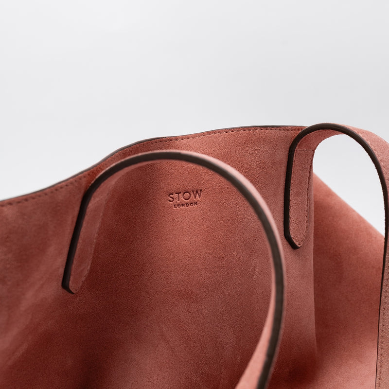 Close up of the small STOW London logo on the Everyday Tote bag in Hazy Blush suede on a light grey background 