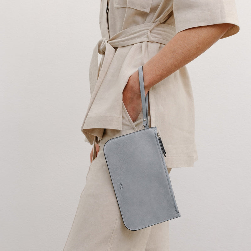 Model wearing the Everyday Tote bag's matching interior pouch on her wrist featuring a small STOW London logo embossed on the front panel