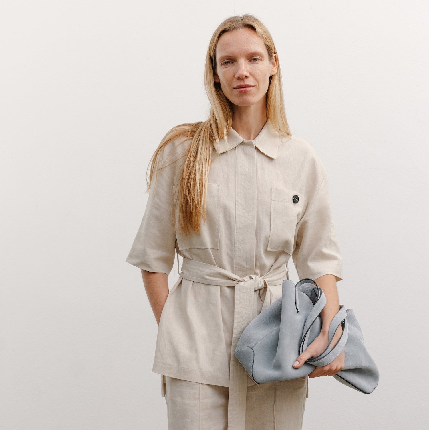 Model with STOW London's Everyday Tote bag in Misty Blue suede featuring a small STOW London logo embossed on the front panel 