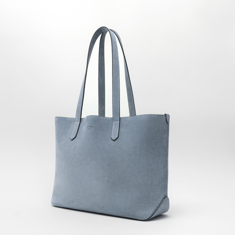 STOW London's Everyday Tote bag in Misty Blue suede on a light grey background featuring a small STOW London logo embossed on the front panel 