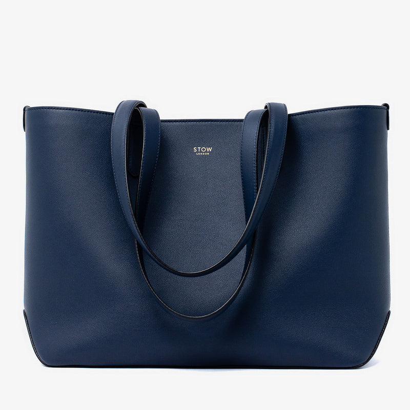 Stow London's Everyday Tote Bag in Navy smooth leather on a light grey background featuring gold STOW logo