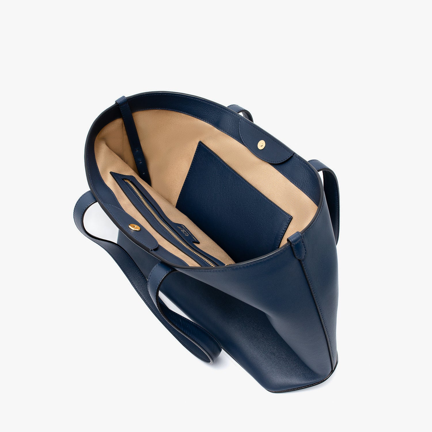 Stow London's Everyday Tote Bag in Navy smooth leather on a light grey background with magnets open showing the interior slip and zip pockets 