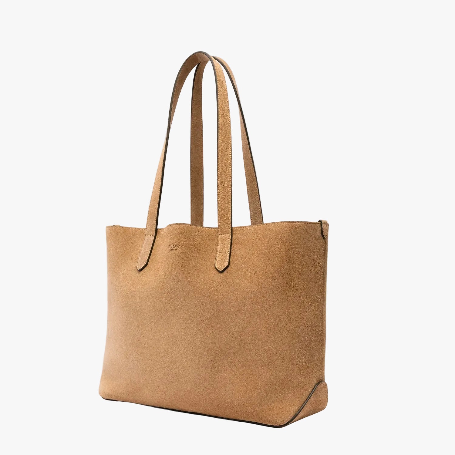 Off-axis view of STOW London's Everyday Tote bag in Soft Sand suede on a light grey background featuring a small STOW London logo embossed on the front panel 