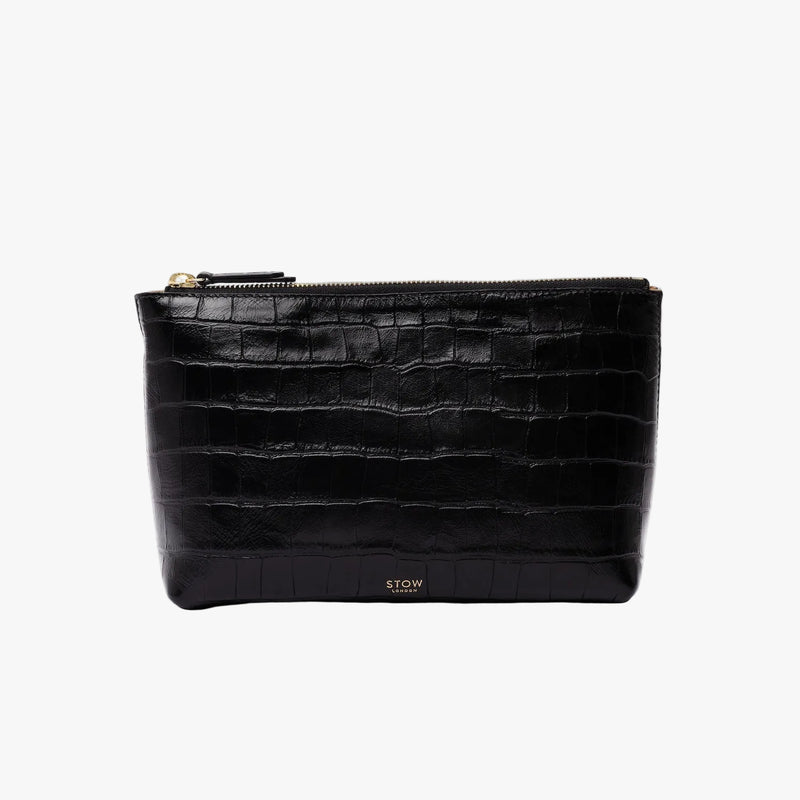 STOW London's travel pouch in Black Embossed Croc leather on a light grey background featuring a YKK zip and a fine gold embossed logo on the front