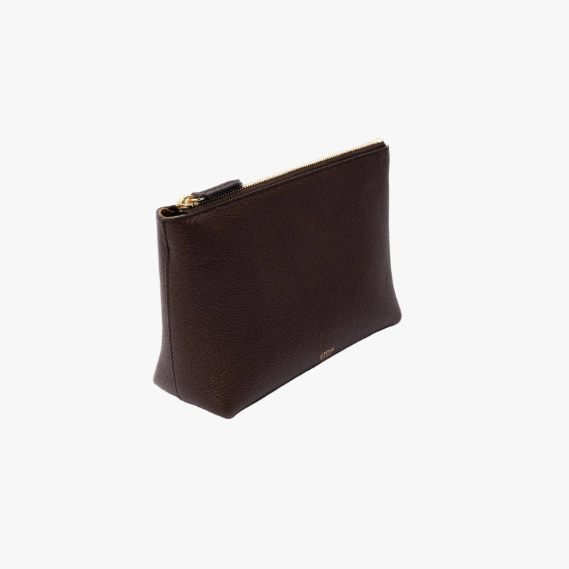 Off-axis view of STOW London's travel pouch in Espresso pebbled leather on a light grey background featuring a YKK zip and a fine gold embossed logo on the front bottom 