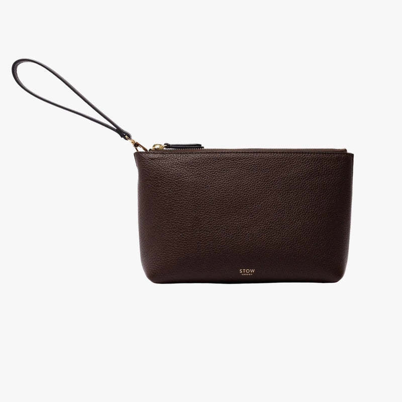 STOW London's travel pouch in Navy pebbled leather on a light grey background featuring its detachable wrist strap, a YKK zip and a fine gold embossed logo on the front bottom 