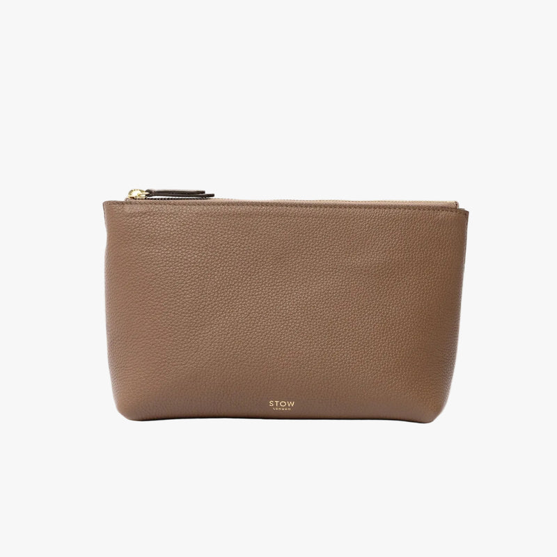STOW London's travel pouch in Mocha pebbled leather on a light grey background featuring a YKK zip and a fine gold embossed logo on the front 