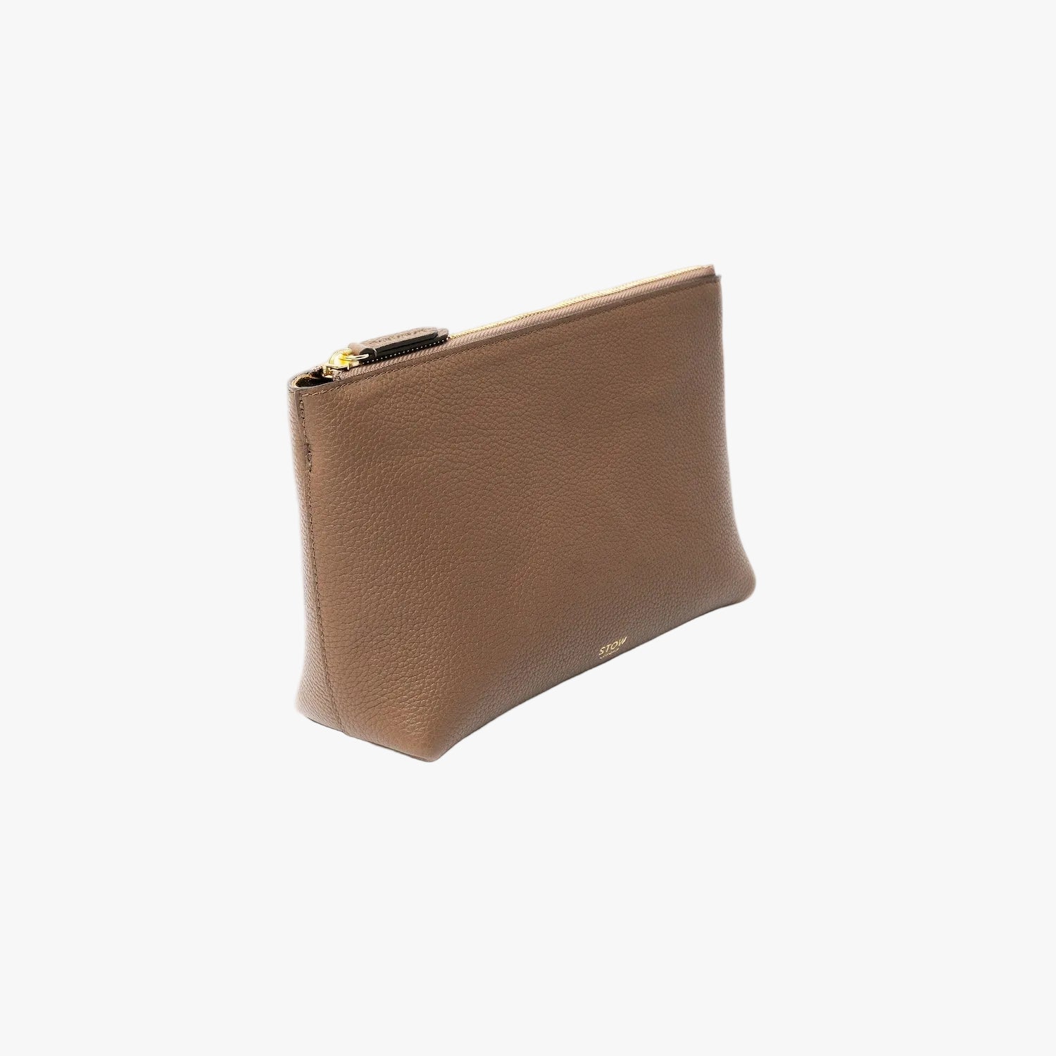 Off-axis view of STOW London's travel pouch in Mocha pebbled leather on a light grey background featuring a YKK zip and a fine gold embossed logo on the front bottom 