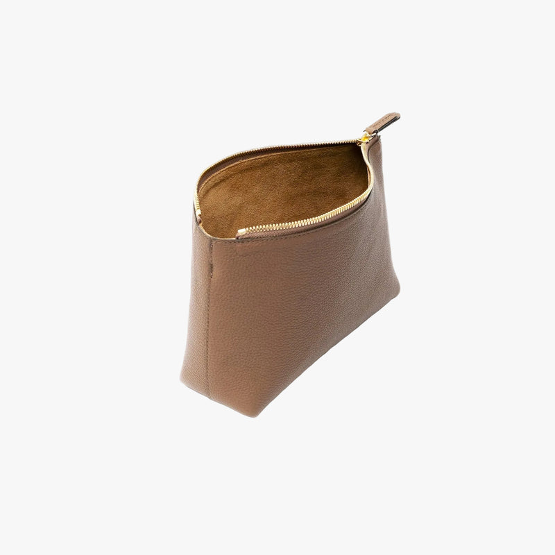 Off-axis view of STOW London's travel pouch in Mocha pebbled leather on a light grey background with the zip open showing the suede interior 