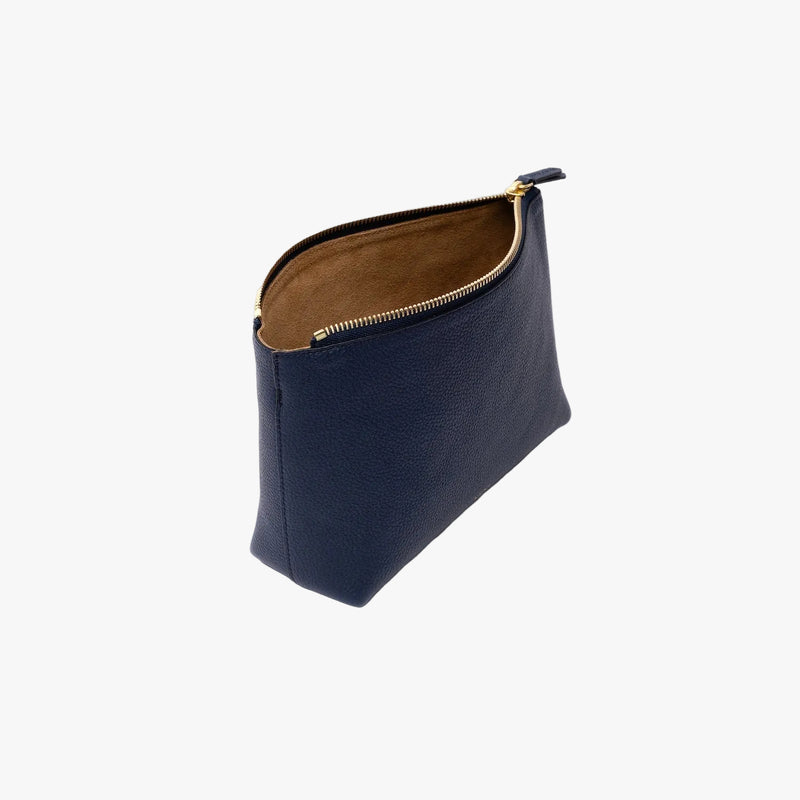 Off-axis view of STOW London's travel pouch in Navy pebbled leather on a light grey background with zipper open showing suede interior