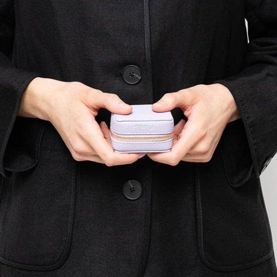 STOW London Mini Essentials Case in Wild Lavender leather held by model wearing all black