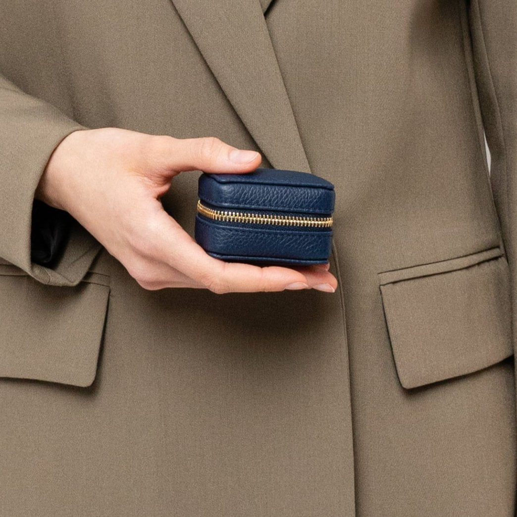 STOW London Mini Essentials Case in Navy leather held by female model in studio wearing green blazer