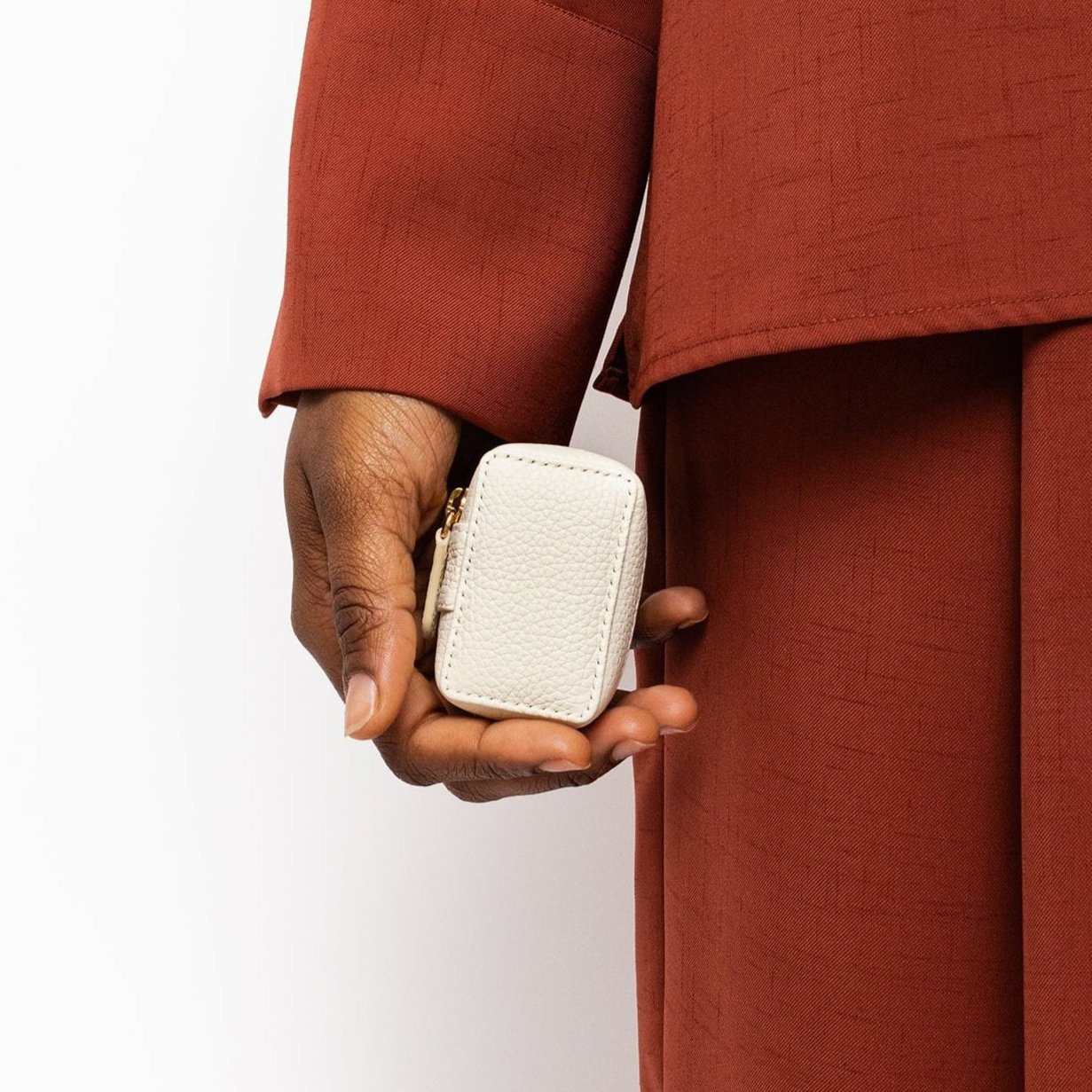 STOW London Mini Essentials Case in Spring Moon leather held in hand of model wearing dark red shirt and trousers