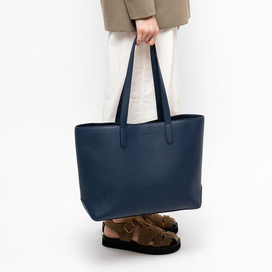 STOW London Navy Leather Everyday Tote Bag, studio image with female model holding bag