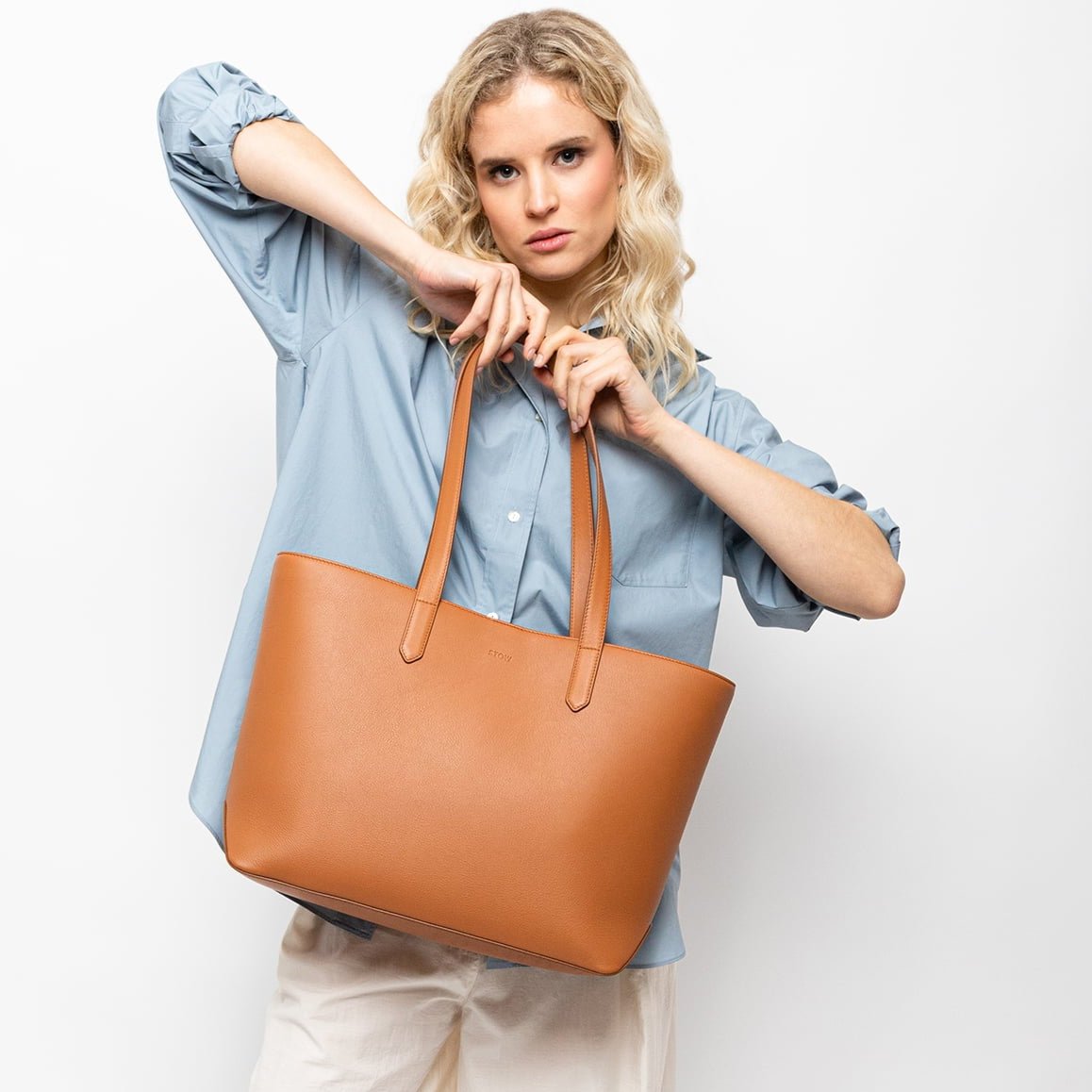 STOW London Earth Tan Leather Everyday Tote Bag, studio image with female model holding bag