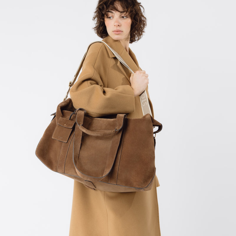Model wearing STOW London's Weekend bag in Chocolate suede leather on her shoulder on a white background