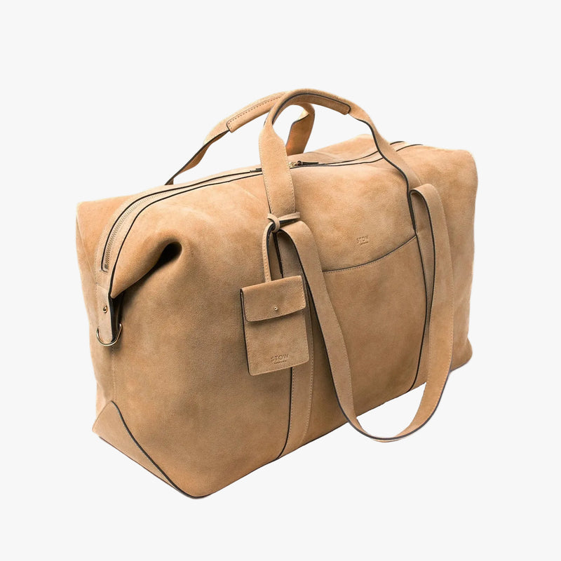Off-axis view of STOW London's Weekend bag in Soft Sand suede on a light grey background 