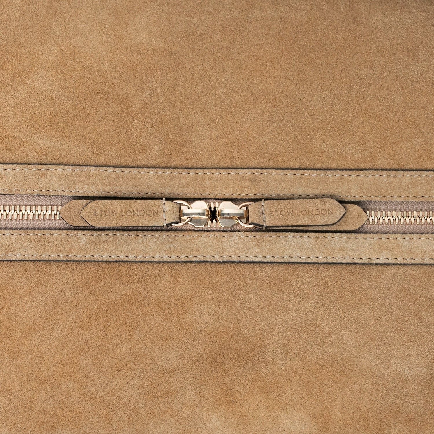Close up of the zip closure on STOW London's Weekend bag in Soft Sand suede on a light grey background 