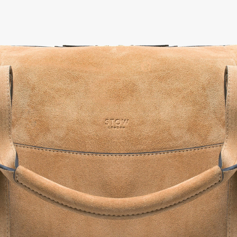 Close up of STOW London logo on the Weekend bag in Soft Sand suede on a light grey background 
