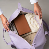 STOW Leather Weekend Bag in Wild Lavender pebbled leather being opened by model showing contents inside.