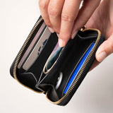 STOW Leather Zip Wallet in Black pebbled leather being held by model, shown open with items inside the wallet.