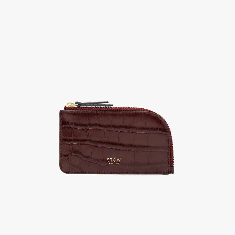 STOW London's Zip Wallet in Burgundy Embossed Croc leather on a light grey background featuring a fine gold embossed logo and YKK Natulon zipper