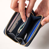 STOW Leather Zip Wallet in Navy pebbled leather being held by model, shown open with items inside the wallet.