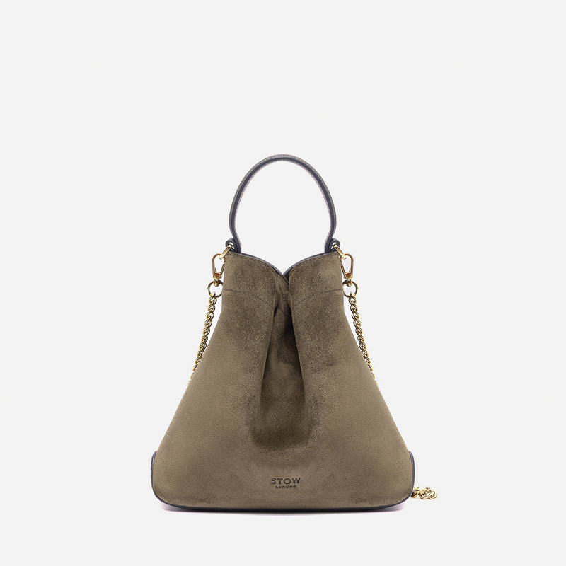 Stow London's Mini Curve in Dark Green suede leather featuring gold-coated stainless steel hardware on a light grey background 